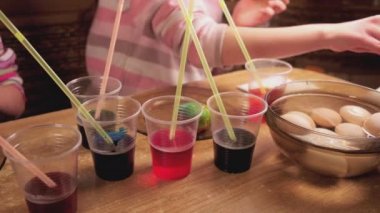 Paskalya, 4K UHD videosu için hazırlanırken kaynamış yumurtalar üzerinde boya ve boya kullanan çocukların videolarını kapat