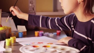 Evdeki boyaları boyamak. Kız güzel çiçekler çiziyor.