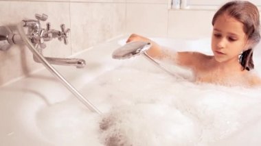 Küçük kız küvette banyo yapıyor ve köpükle oynuyor, hijyen ve bebek bakımı konsepti, 4K UHD hala video kamera, 2x yavaş çekim.