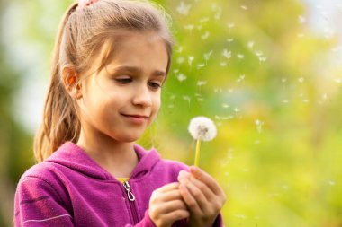 Küçük güzel kız elinde bahar karahindibası tutuyor. Yaz eğlencesi, tatlı kız çayırda karahindiba