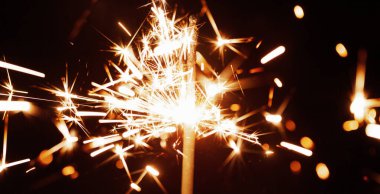 Altın sarısı bulanık kıvılcımların yakın çekimi, neşeli mumların ışığından karanlıkta yanar. Havai fişek konsepti ve tatiller için tebrikler ve mutlu yıllar. Kopyalama alanı