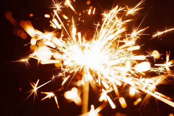 お祝いのろうそくの光から暗闇の中で燃える黄金のぼやけた火花のクローズアップ 休日や幸せな新年に花火やお祝いの概念 コピースペース — ストック写真