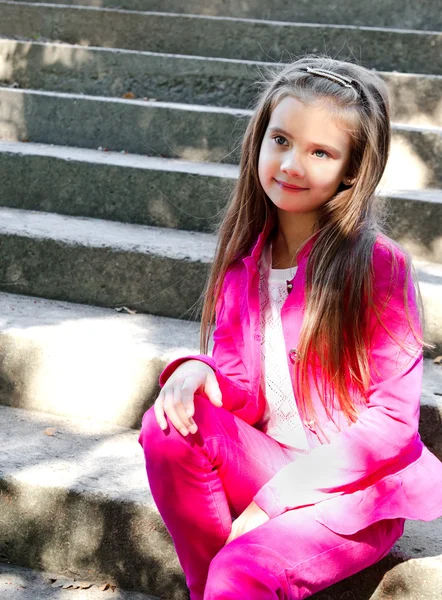 Portrait of adorable smiling little girl sitting on the steps of — Stock Photo, Image
