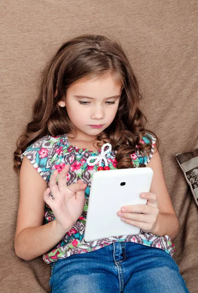 Schattig klein meisje met tablet pc op de sofa thuis — Stockfoto