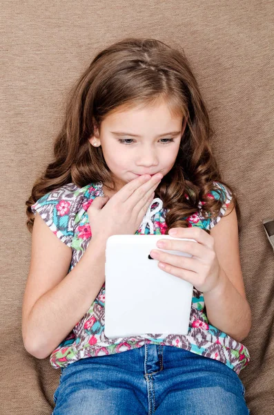 Schattig klein meisje met tablet pc op de sofa thuis — Stockfoto