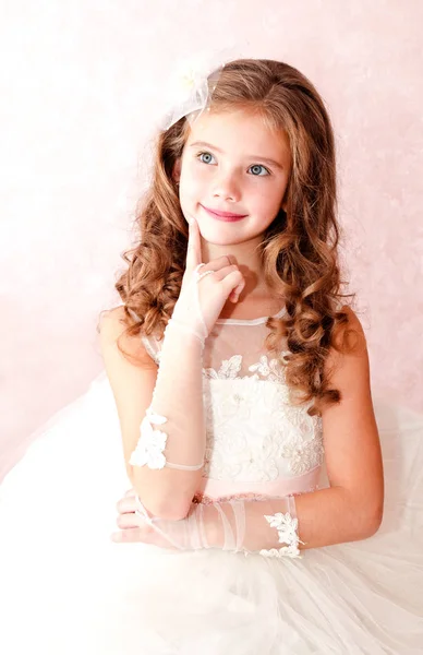 Adorable smiling little girl is dreaming in white princess dress — Stock Photo, Image