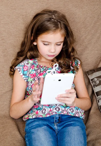 Schattig klein meisje met tablet pc op de Bank — Stockfoto