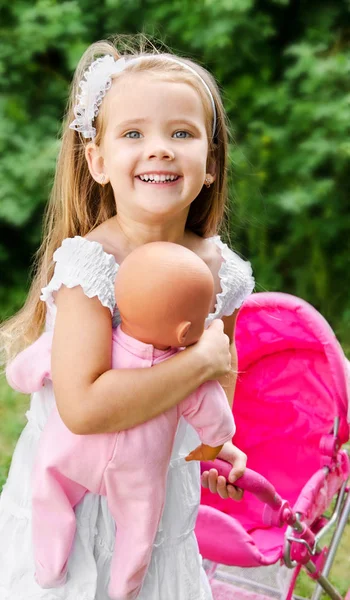 Cute little girl with her toy carriage and doll — Stock Photo, Image