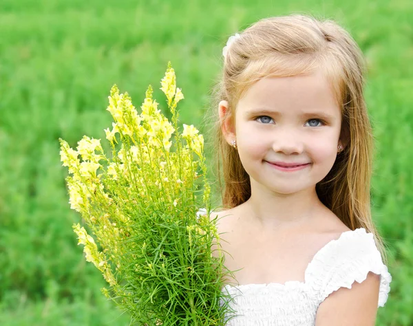 Ler söt liten flicka med blommor på ängen — Stockfoto