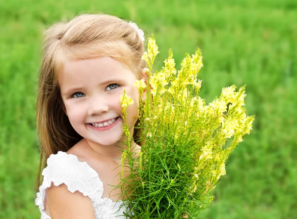 Sorrindo menina bonito com flores no prado — Fotografia de Stock