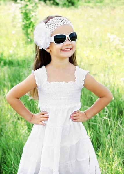Carino sorridente bambina in occhiali da sole sul prato — Foto Stock