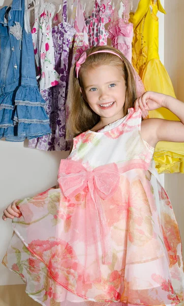 Cute smiling little girl chooses a dress from the wardrobe — Stock Photo, Image