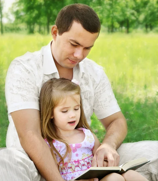Pappa med dotter läsa i parken — Stockfoto