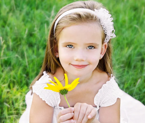 Schattig klein meisje op de weide met bloem — Stockfoto