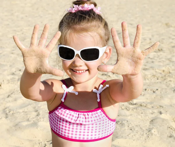 小さな女の子がビーチで遊んでの笑みを浮かべてください。 — ストック写真