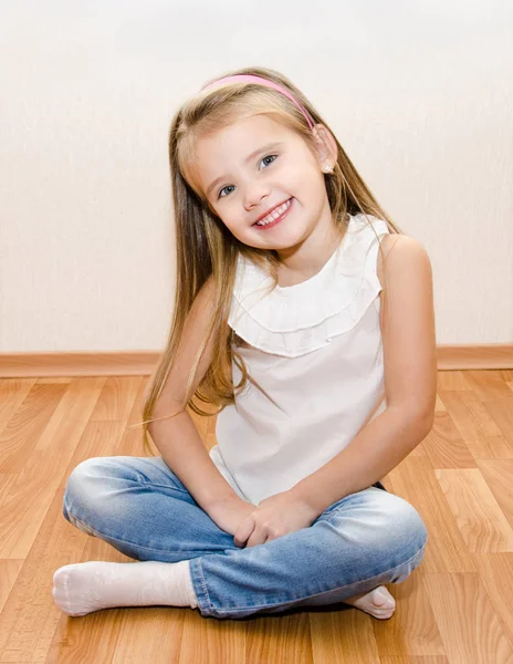 Smiling cute little girl sitting on floor — Stock Photo, Image