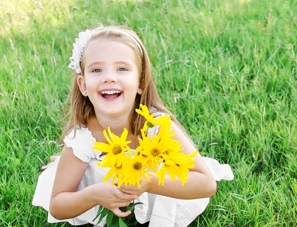 Schattig klein meisje op de weide met bloem in zomerdag — Stockfoto