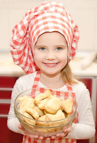 Leende liten flicka i kock hat håller skål med cookies — Stockfoto