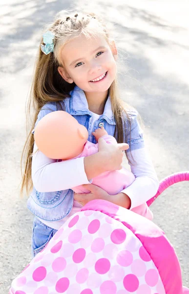 Süßes lächelndes kleines Mädchen spielt mit ihrem Spielzeugwagen — Stockfoto