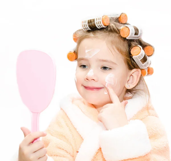 Happy cute little girl in hair curlers with mirror applying crea — Stock Photo, Image