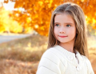 Sonbahar portre sevimli küçük kız parkta gülümseyen