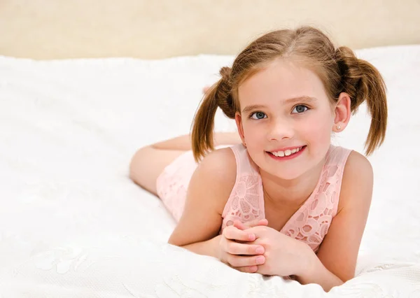 Adorable petite fille souriante se repose sur un lit — Photo