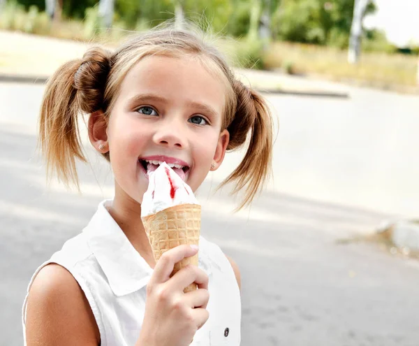 Милая улыбающаяся маленькая девочка ест мороженое — стоковое фото