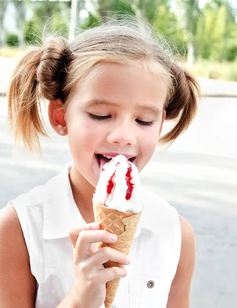 Милая улыбающаяся маленькая девочка ест мороженое — стоковое фото