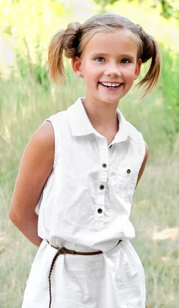 Портрет очаровательной улыбающейся маленькой девочки в платье на открытом воздухе — стоковое фото