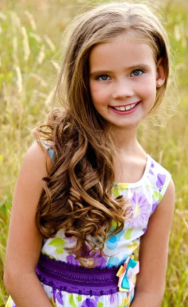 Портрет очаровательной улыбающейся маленькой девочки на лугу в сумме — стоковое фото