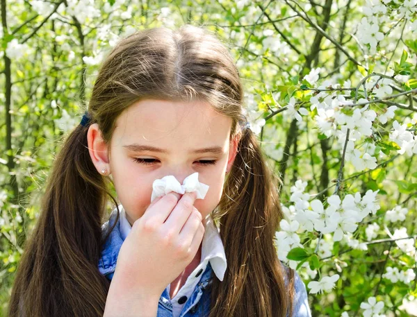 Niña tiene alergia a la primavera floreciendo y soplando sus nos — Foto de Stock