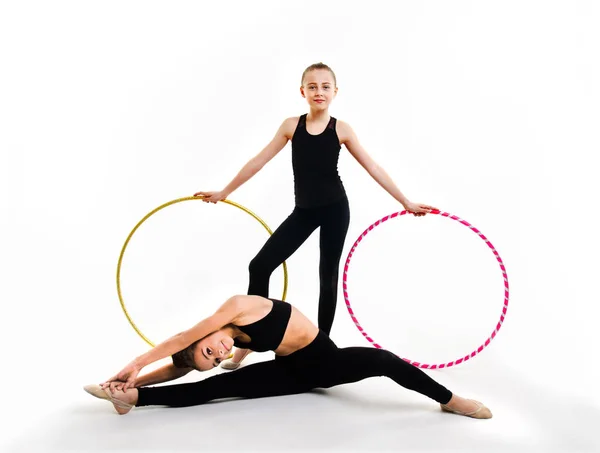 Дві гнучкі милі маленькі дівчата гімнастки роблять акробатичні вправи — стокове фото