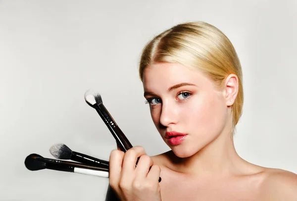 Ritratto di bella bionda giovane donna faccia holding make up br — Foto Stock