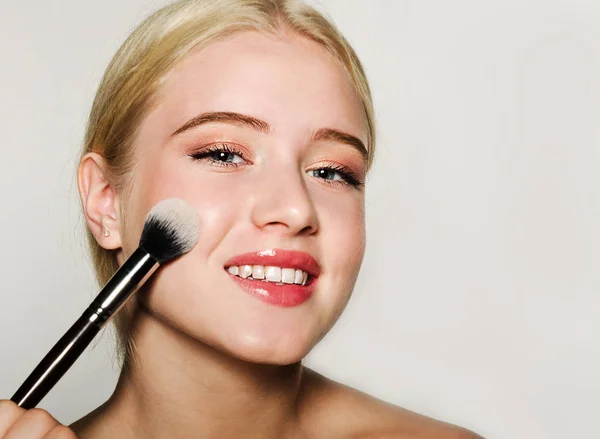 Retrato de hermosa rubia joven cara sosteniendo maquillaje br — Foto de Stock