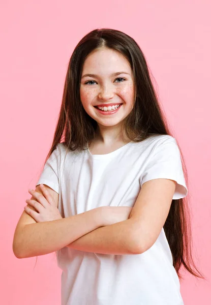 ピンクの背景に隔離された白いTシャツのかわいい笑顔の女の子の子供の肖像画 — ストック写真