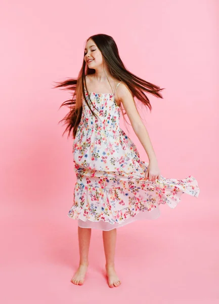 在粉色背景下孤零零地穿着衣服跳舞的可爱微笑小女孩的画像 — 图库照片