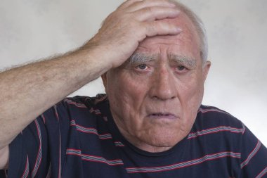 Yaşlı bir adam başını tutan