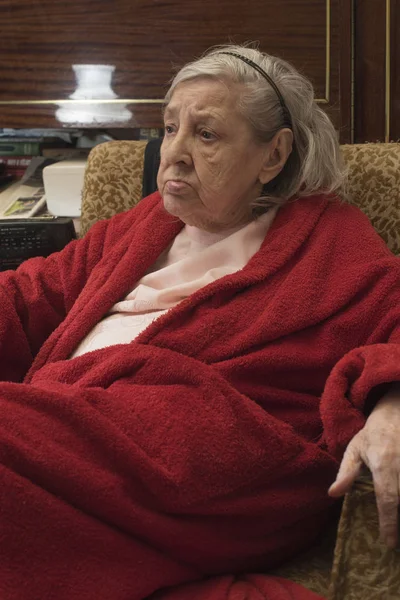 Mujer mayor en bata roja relajándose en una silla —  Fotos de Stock