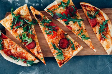 Dilimleri lezzetli taze pizza domates, biber ve bira ile karanlık bir arka plan üzerinde kesmek. Üstten Görünüm.