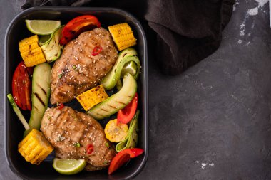 Siyah bir zemin üzerine Sebzeli tavuk ızgara fileto.