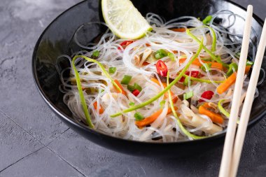 Vietnamca Pho çorbası. Siyah bir arka plan üzerinde çubuklarla aldı erişte gösterilen fasulye biber, pirinç noodle, vuruyor.