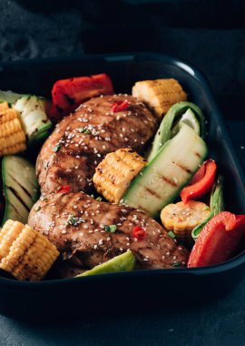 Siyah bir zemin üzerine Sebzeli tavuk ızgara fileto.