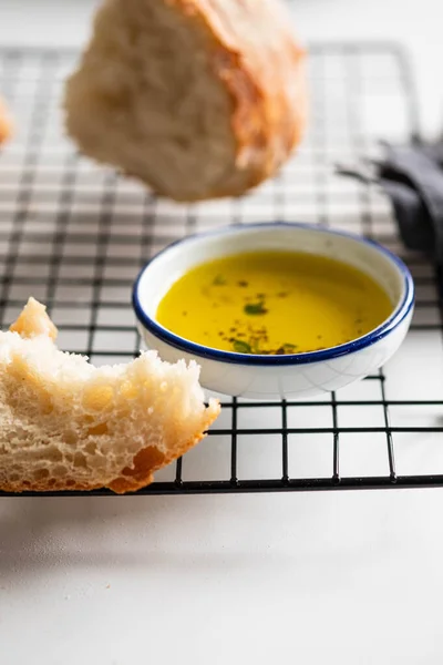 Nybakat vitt bröd med olivolja och örter på vit bakgrund. — Stockfoto