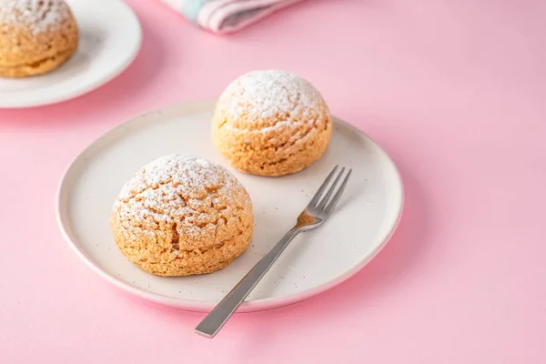 Biscoitos Craquelin Choux com recheio de creme em um fundo rosa . — Fotografia de Stock