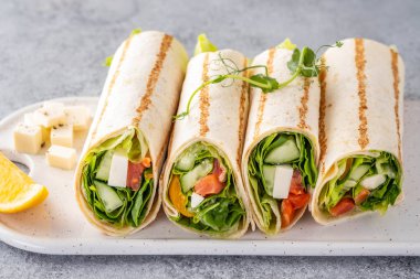 Sandviç paketle, balık somon, sebze ve peynirle yuvarlan. Gri arka plan. Kapat..