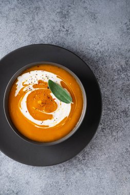 Gri arka planda adaçayı ile kabak çorbası. Üstte görüntü.