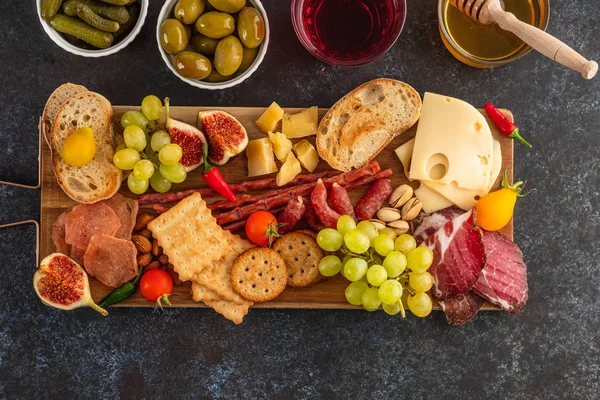 Antipasto prato de catering com bacon, jerky, salsicha, azeitona, queijo e uvas em uma tábua de madeira. Vista superior . — Fotografia de Stock