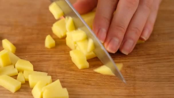 Tangan wanita memotong kentang mentah dengan pisau di papan kayu. Mengiris kentang. Membuat sup . — Stok Video