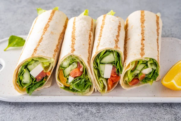 Envuelva el sándwich, rollo con salmón de pescado, verduras y queso. Fondo gris. De cerca. . —  Fotos de Stock
