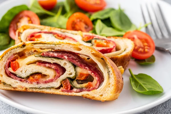 Italiensk mat Pizzarulle stromboli med ost, salami, spenat och röd paprika en lätt bakgrund. — Stockfoto